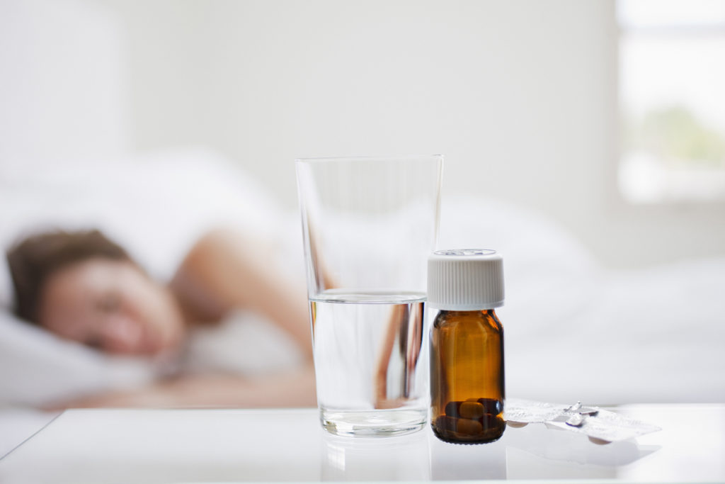 pill bottle with water in foreground insomnia