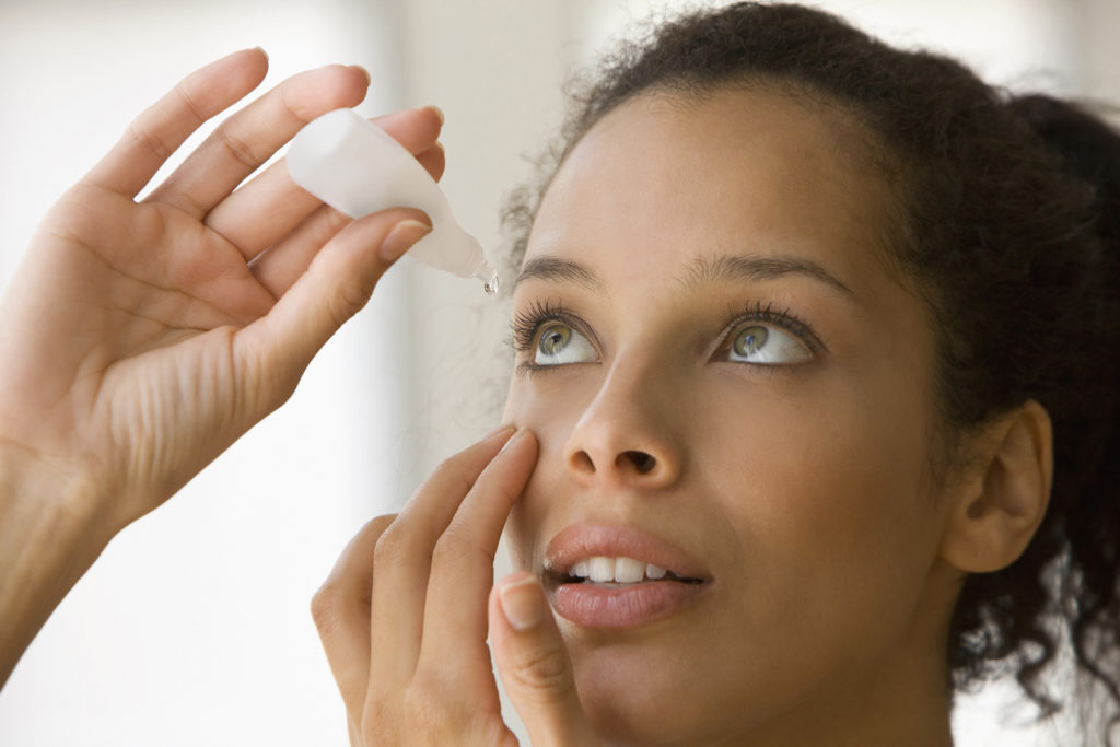 Young woman putting eye drops in