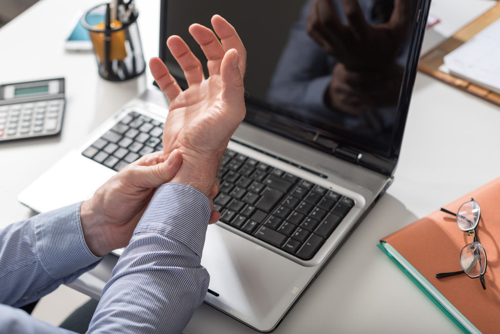 Businessman suffering from wrist pain in office