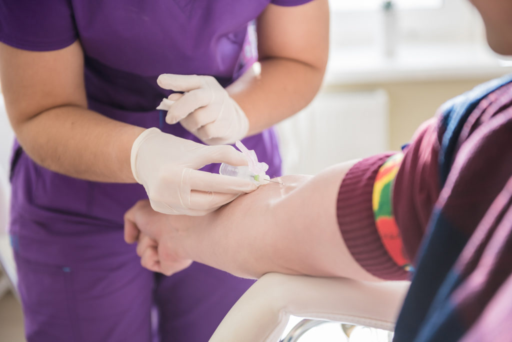 Nurse taking a patient's blood sample at lab.