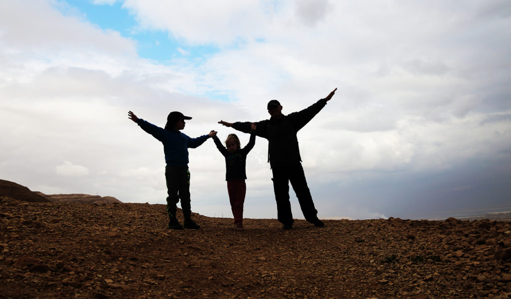 silhouette of father with two kids hiking together