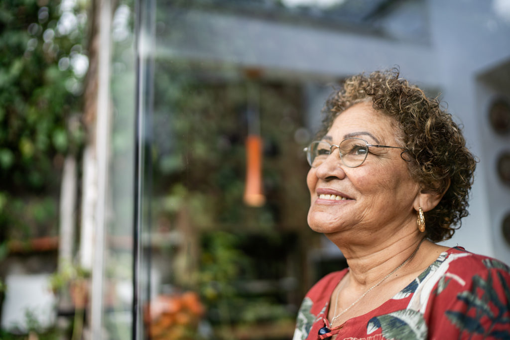Senior woman looks out window, happy
