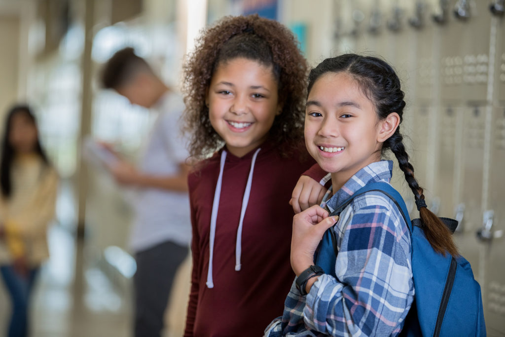 Two happy girls in middle school, lockers