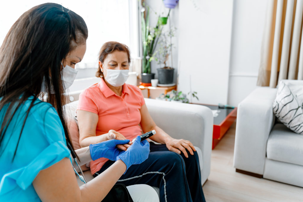Woman getting blood sugar checked by nurse during COVID