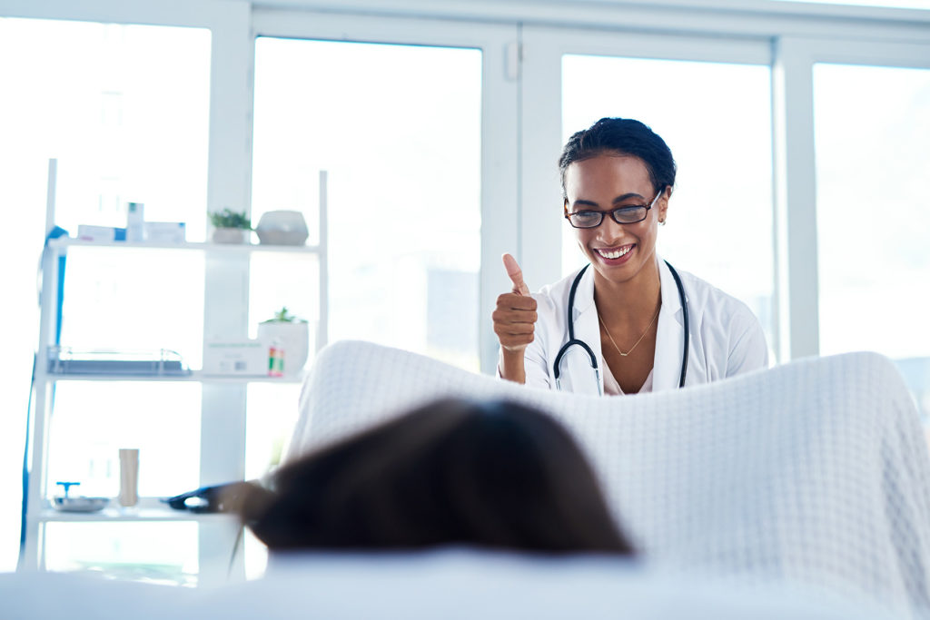 Gynecologist in exam room giving a thumbs up