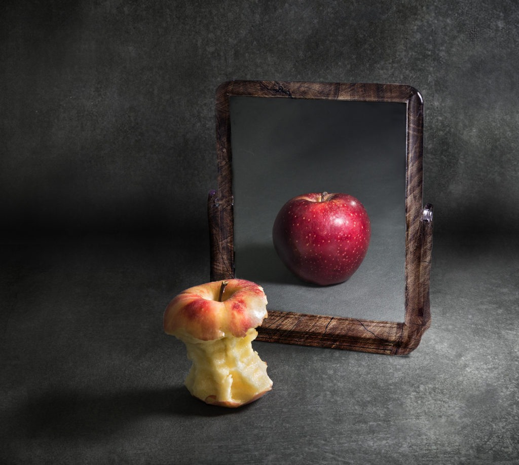 apple with anorexia looking at its reflection in a mirror