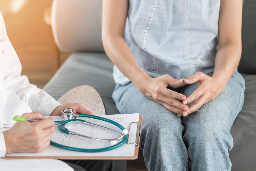 Doctor and Woman consult. Arms and legs in shot.