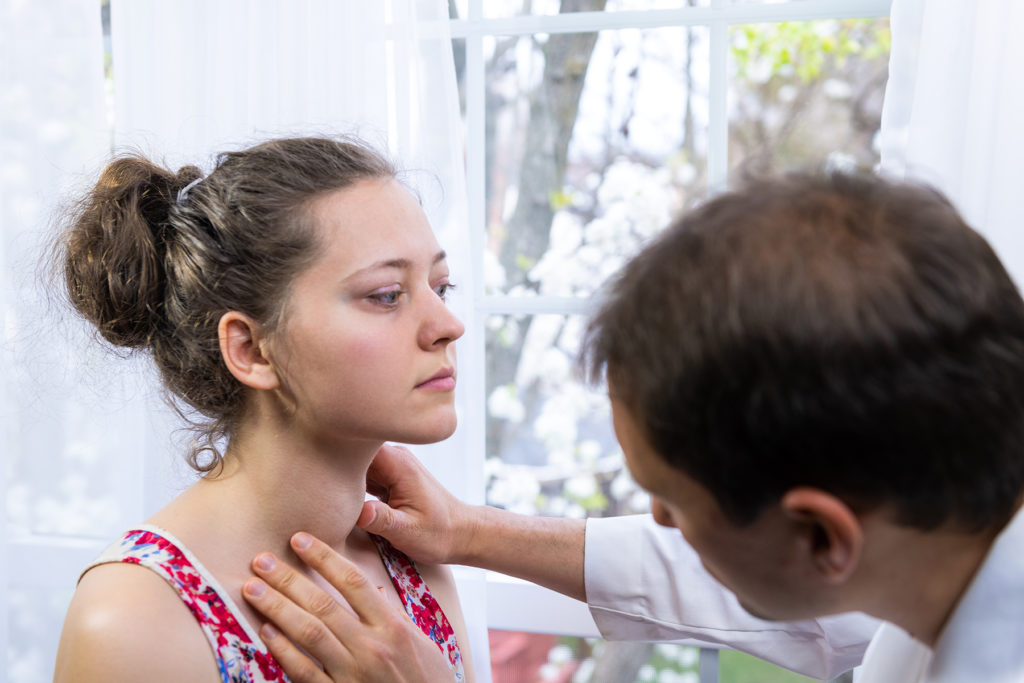 Doctor inspecting woman's thyroid