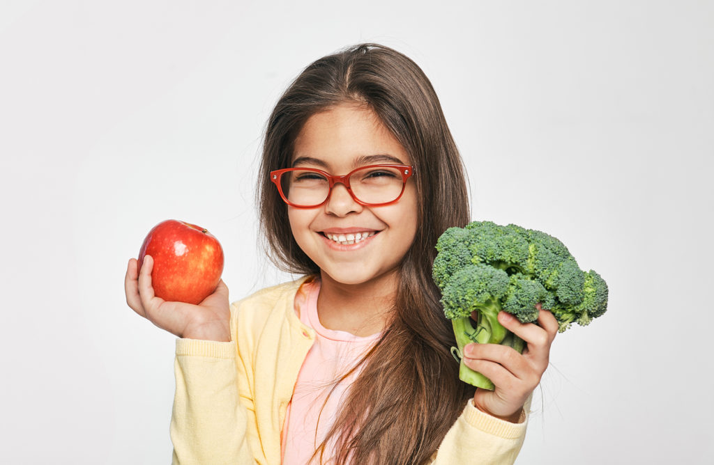 young girl holding vegetables