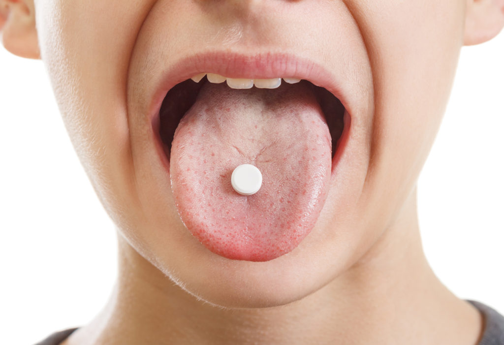 close-up of boy's tongue with small pill on it