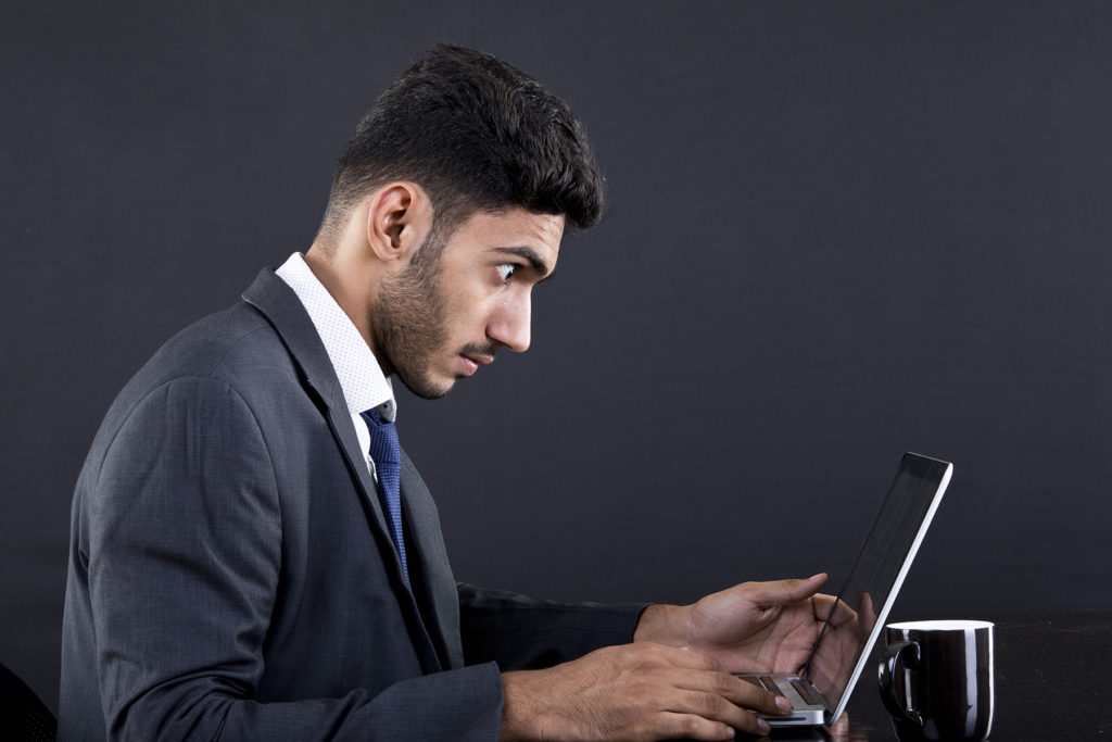 Man reading surprising news on laptop