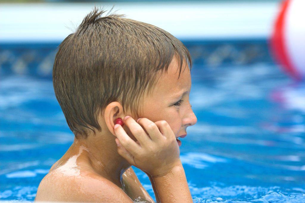 boy in pool holding ear