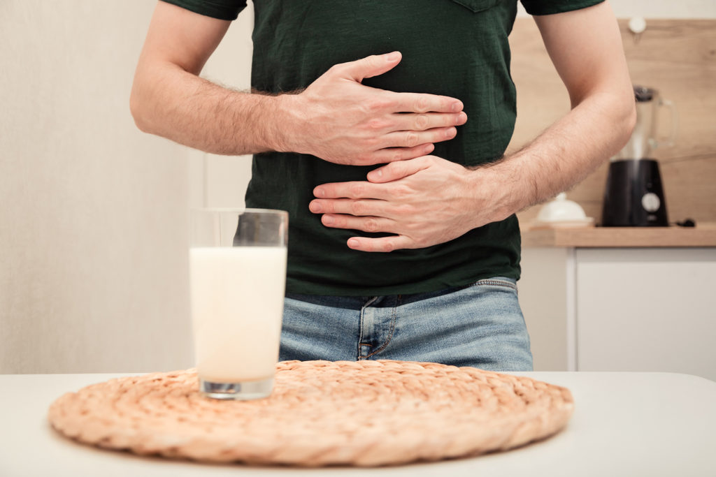 Lactose intolerance - man stands uncomfortable near milk
