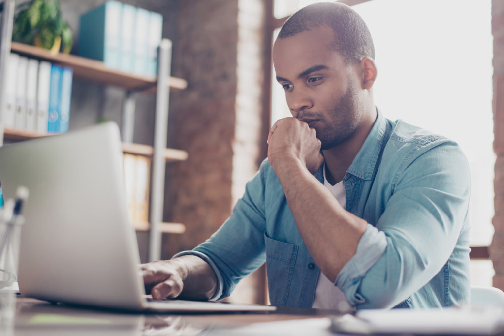 Skeptical young man reads something on laptop