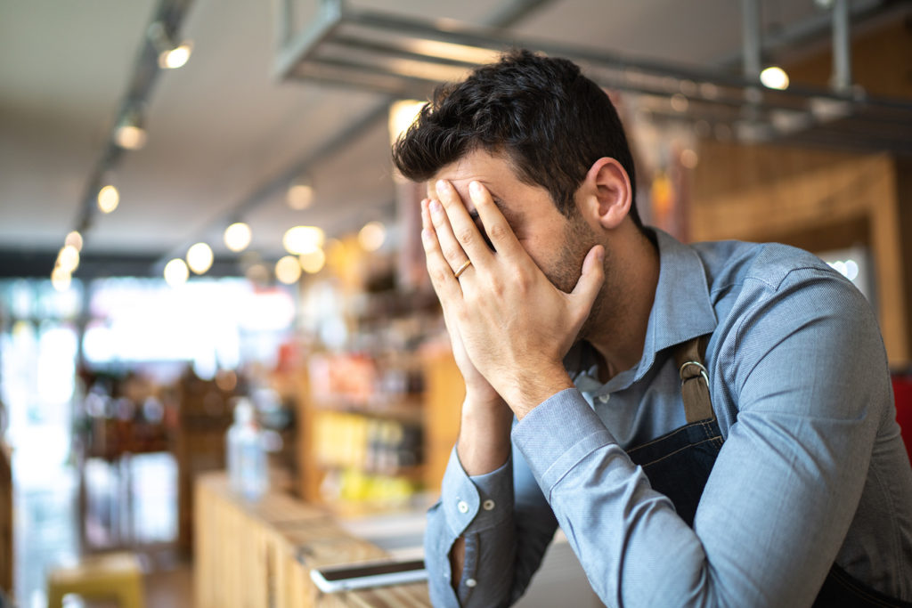 Man with face in hands in an empty business