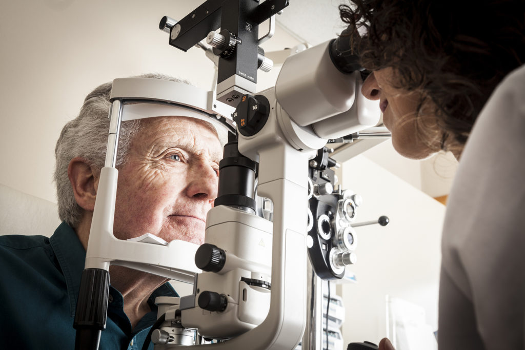 Optometrist giving eye exam to senior looking for cataracts